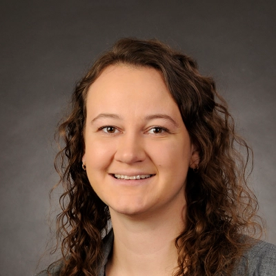 Chiropractor Malorie Konkol Smiling In Front Of Grey Background